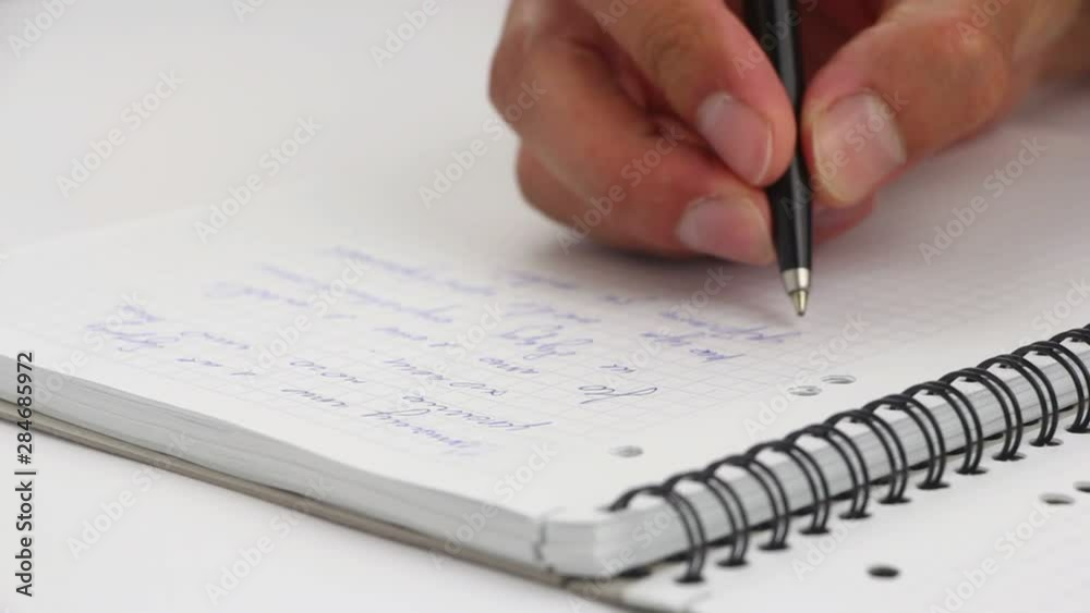 A man writes with a pen in his notebook A man writes with a pen in his notebook
