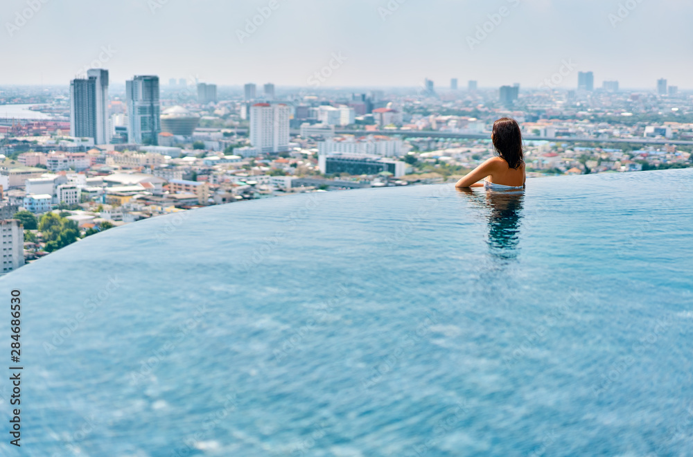 Young woman relax on the edge of the roof top swimming pool