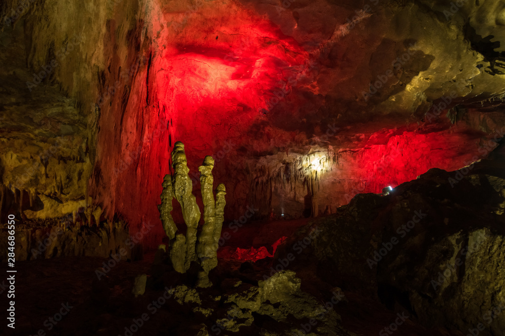 Yellow stalagmites on a red background in the cave of Prometheus, Georgia