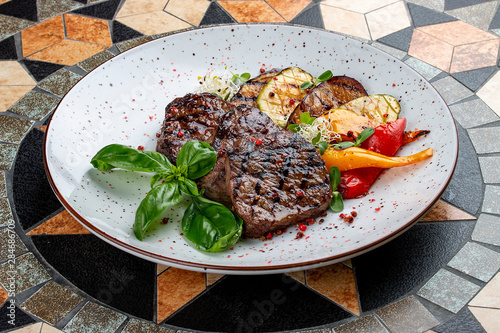 Grilled veal steak with vegetables and basil