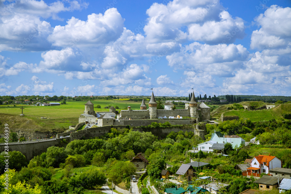 Eastern European national UNESCO heritage object in Ukraine medieval castle old landmark top view on green hills in clear weather time with blue sky and white clouds 