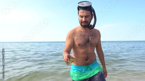 Fisherman in diving mask with crabs in hand. Hand holding crab. Catcher shows crab to camera.