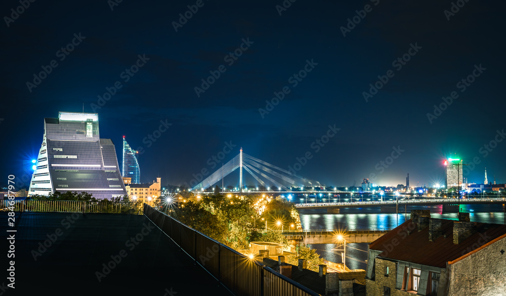 Obraz premium Panoramic view of Riga city with colorful fireworks glowing in the air. Picturesque scene of National library of Latvia, river Daugava and old town. 