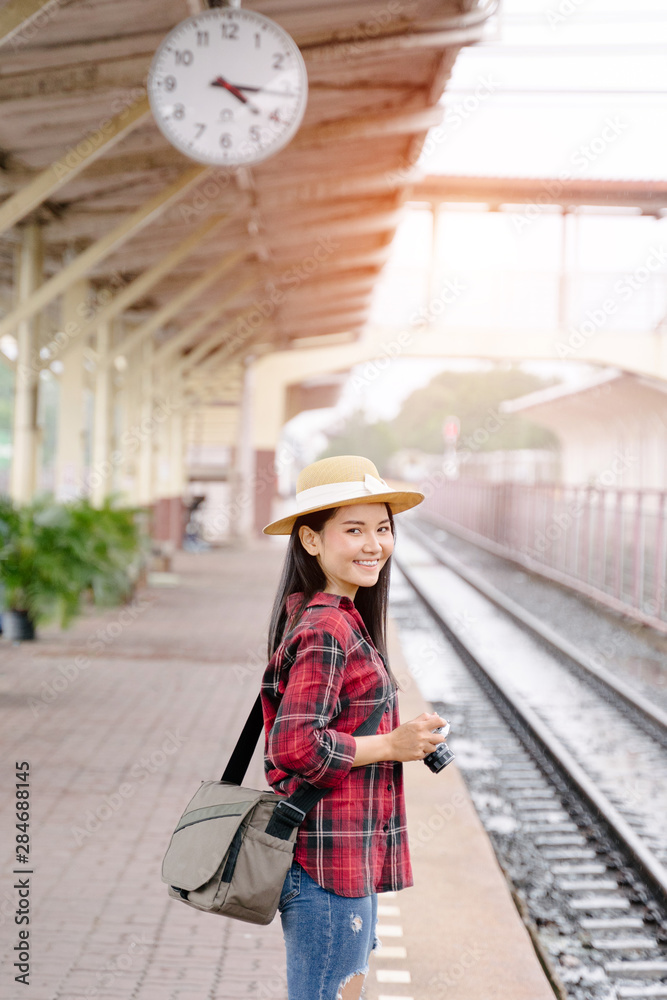 A pretty young woman traveler having fun traveling and taking photo at railway station in evening with vintage camera . The traveling photographer takes photo with old vintage camera at train station.