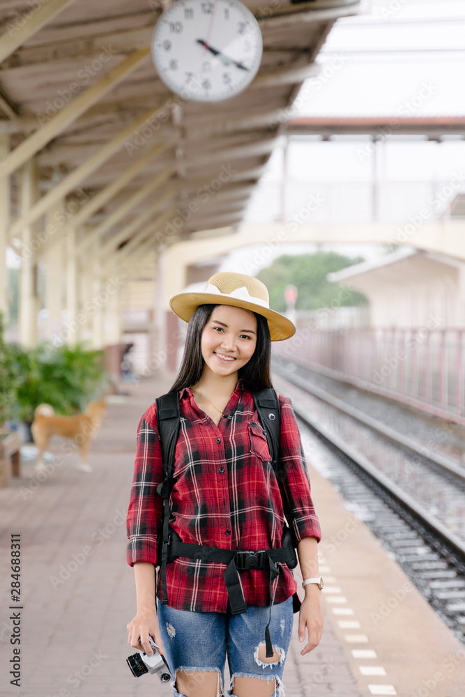 A pretty young woman traveler having fun traveling and taking photo at railway station in evening with vintage camera . The traveling photographer takes photo with old vintage camera at train station.