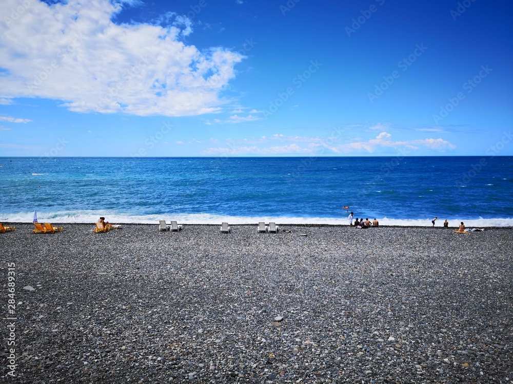 sea coast, pebble beach. people sunbathe on the seashore. relax
