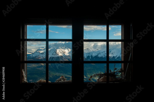 Snowy mountains framed by alpine hut window