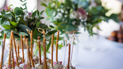 Bamboo sticks on a sweet table decorated with some green flowers and some pink rose blossom