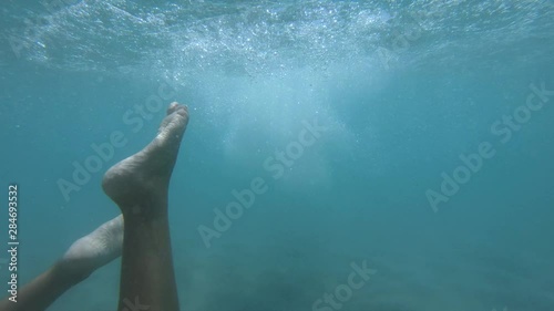 Underwater view of a little girl diving down and swimming towards camera in the sea photo