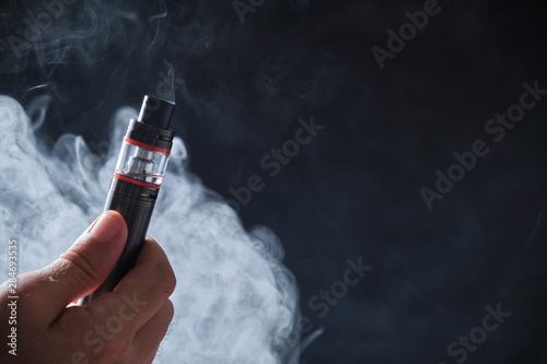 Electronic cogarette vape on a dark background with steam photo