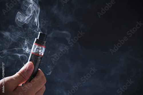 Electronic cogarette vape on a dark background with steam photo