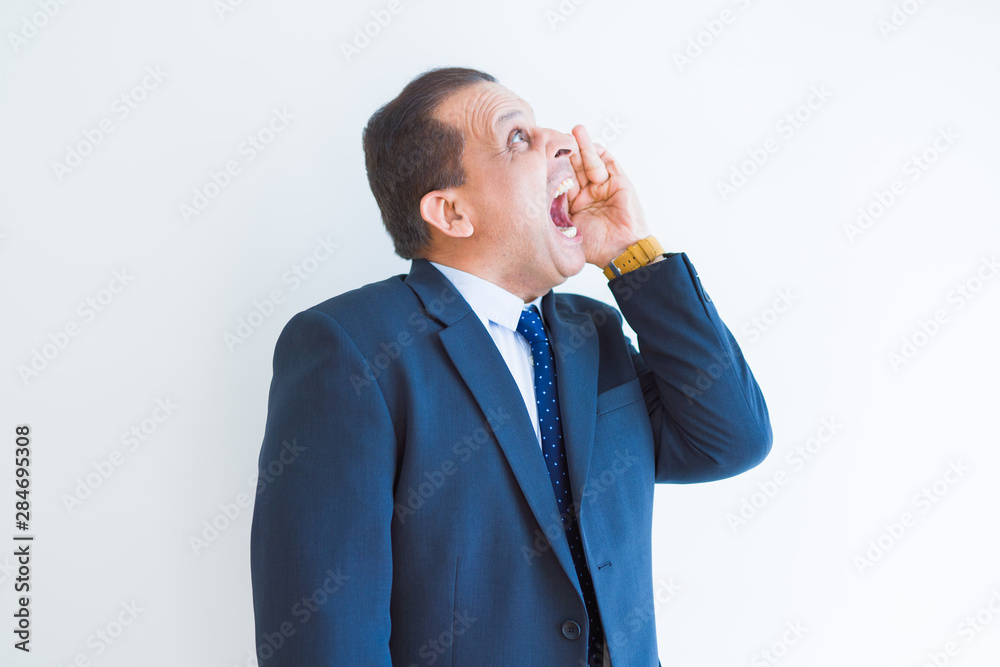 Middle age man shouting crazy with hands over mouth over white wall background Middle age man shouting crazy with hands over mouth over white wall background
