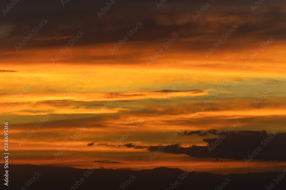 Abstract nature background. Dramatic sunset sky in the clouds saturated with bright colors of orange and yellow. Contrast Low Key