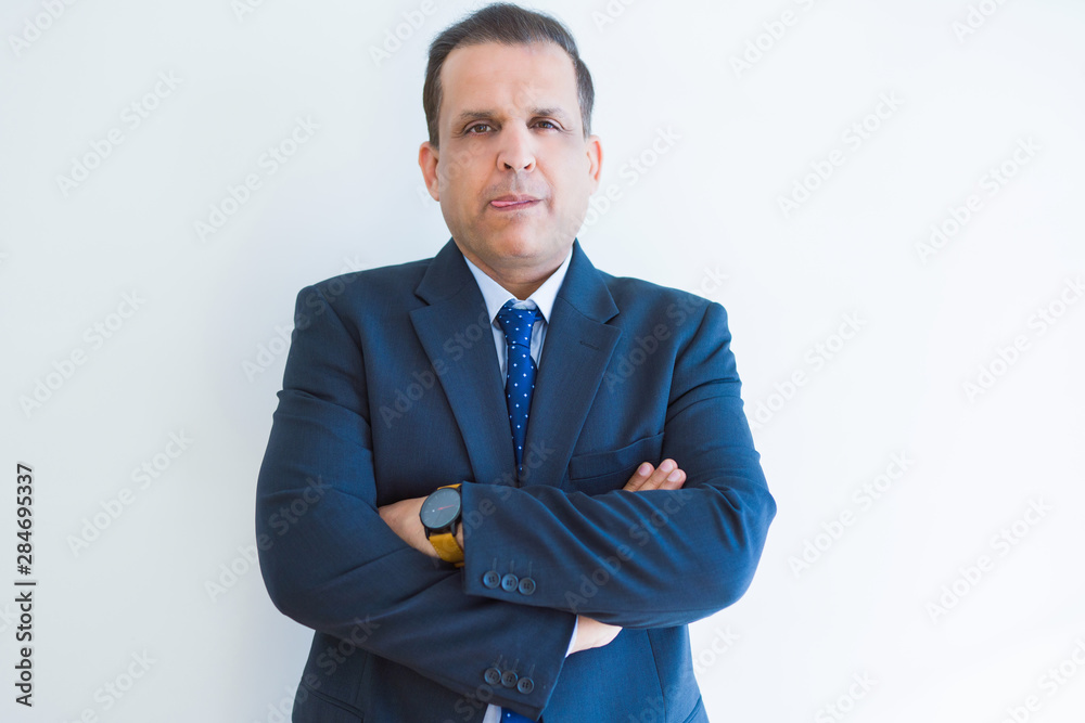 Middle age business man looking natural and relaxed with crossed arms over white wall background Middle age business man looking natural and relaxed with crossed arms over white wall background