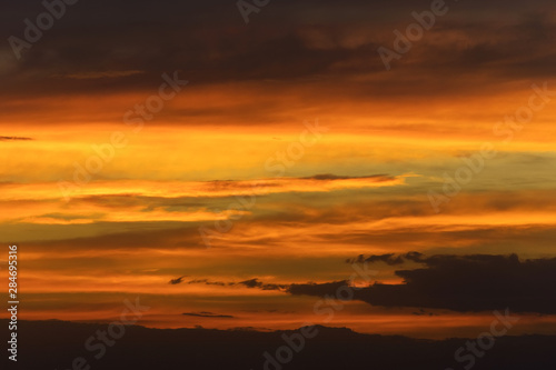 Abstract nature background. Dramatic sunset sky in the clouds saturated with bright colors of orange and yellow. Contrast Low Key