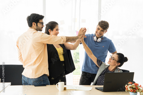 Happy successful multiracial business team giving a high fives gesture as they laugh and cheer their success