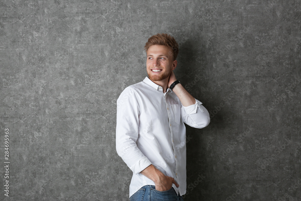 Portrait of handsome young man near grey wall