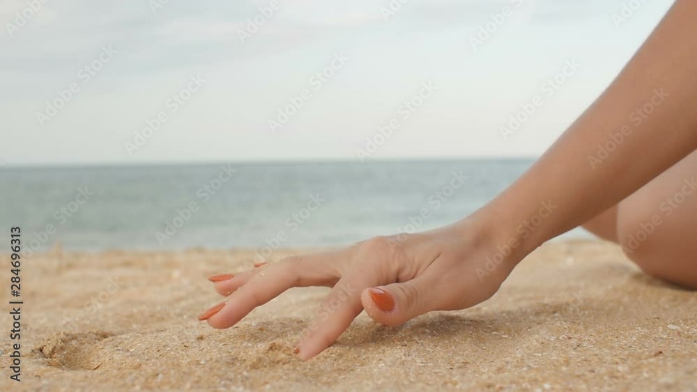 Sea shell in female hand at the beach, sand pouring down, summer day on beach and vacation relax concept Sea shell in female hand at the beach, sand pouring down, summer day on beach and vacation relax concept