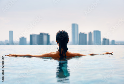 Photography Bavk view of young woman swimming in swimming pool on roof top