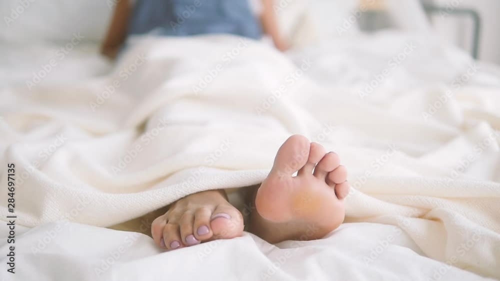 Female legs in bed. Beautiful pedicure. Close-up legs on white underwear Female legs in bed. Beautiful pedicure. Close-up legs on white underwear