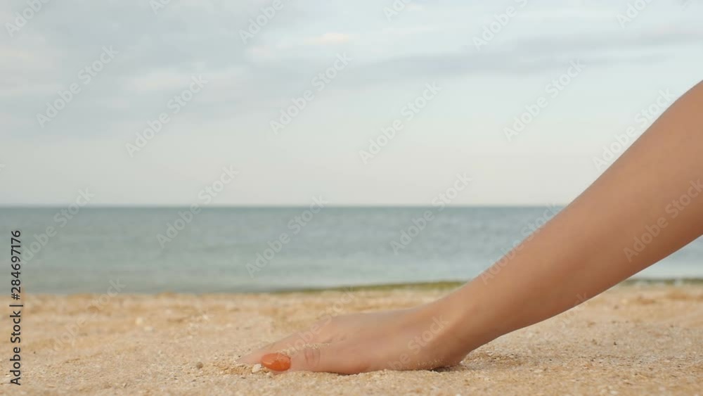 Sea shell in female hand at the beach, sand pouring down, summer day on beach and vacation relax concept Sea shell in female hand at the beach, sand pouring down, summer day on beach and vacation relax concept