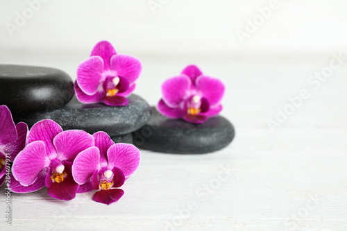 Spa stones and orchid flowers on white wooden table, space for text