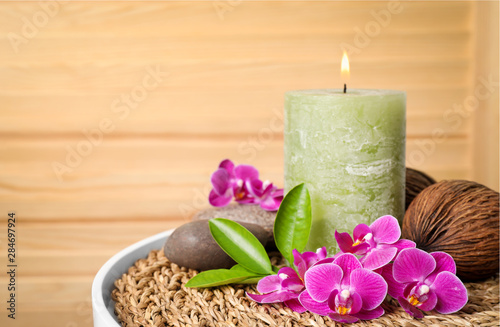 Composition with candle  spa stones and orchid flowers on table against wooden background