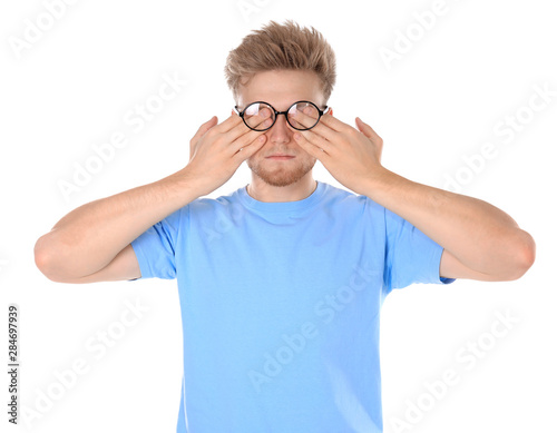 Young man with glasses covering eyes on white background