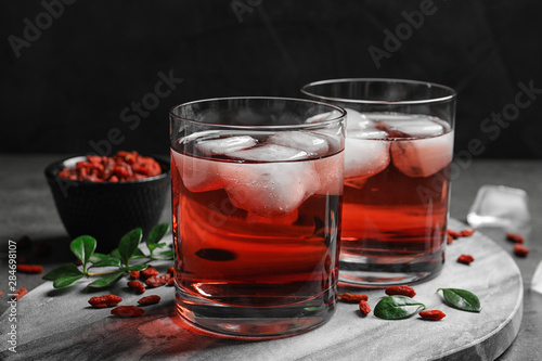 Healthy goji juice with ice in glasses on table