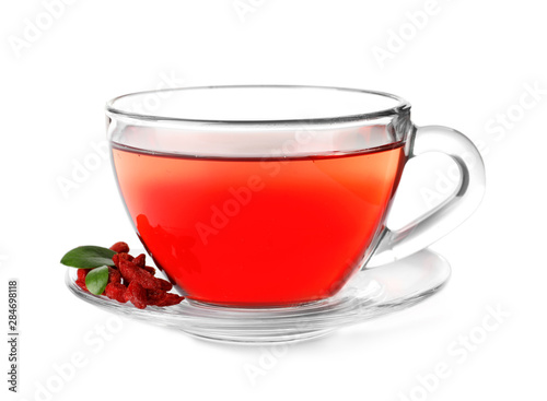 Healthy goji tea in glass cup with berries on white background