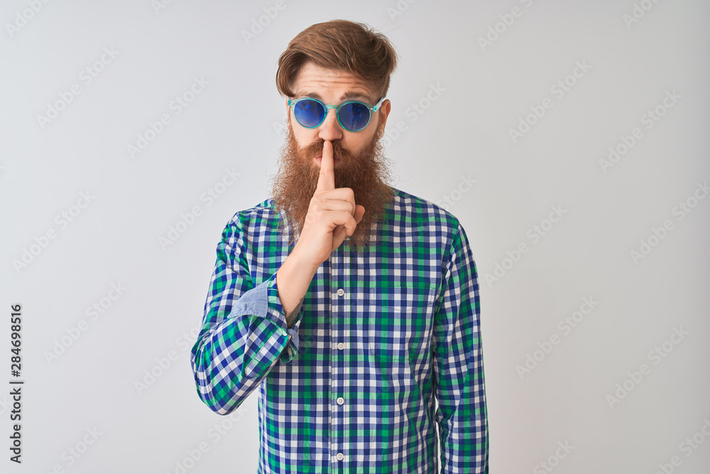 Young redhead irish man wearing casual shirt and sunglasses over isolated white background asking to be quiet with finger on lips. Silence and secret concept. Young redhead irish man wearing casual shirt and sunglasses over isolated white background asking to be quiet with finger on lips. Silence and secret concept.
