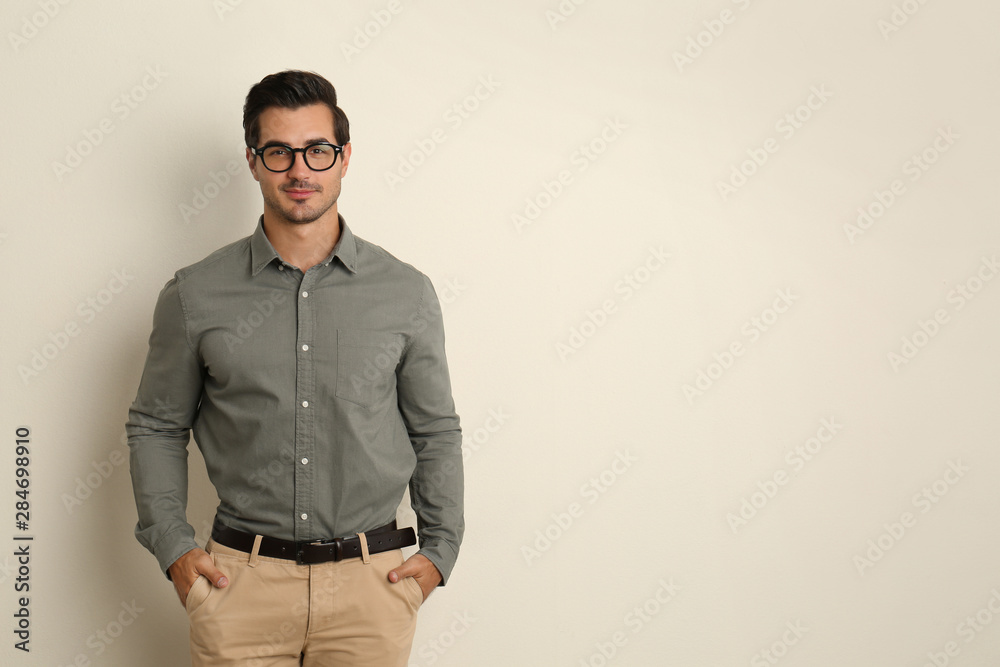 Fototapeta premium Young male teacher with glasses on beige background. Space for text