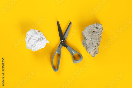 Flat lay composition with rock, paper and scissors on yellow background photo