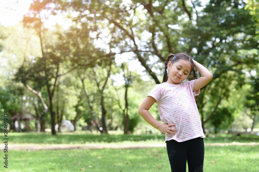 Little girl posting cute &confused action with green park background