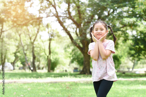Little girl posting cute action with green park background