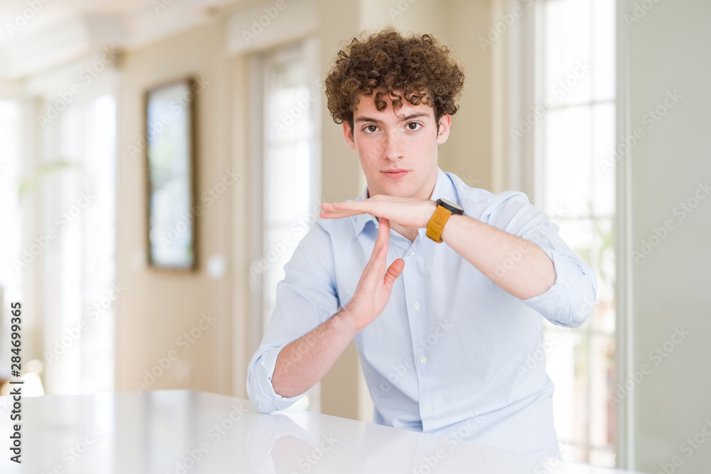 Young business man with curly read head Doing time out gesture with hands, frustrated and serious face