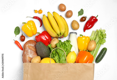 Fototapeta Naklejka Na Ścianę i Meble -  Shopping paper bag with different groceries on white background, top view