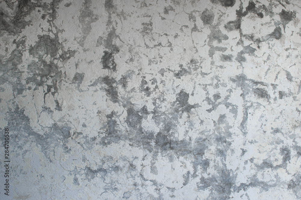 Fototapeta premium A gray concrete wall with a vertical lighting gradient interspersed with white plaster and paint. Background