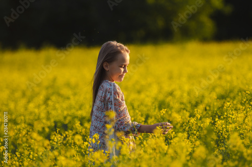 The concept of health and youth. Carefree young girl enjoys the sunset in a canola field. © olga_polyanskaya
