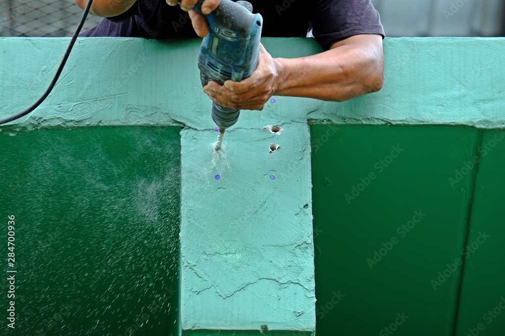 Worker drilling the hole into concrete beam with electric concrete