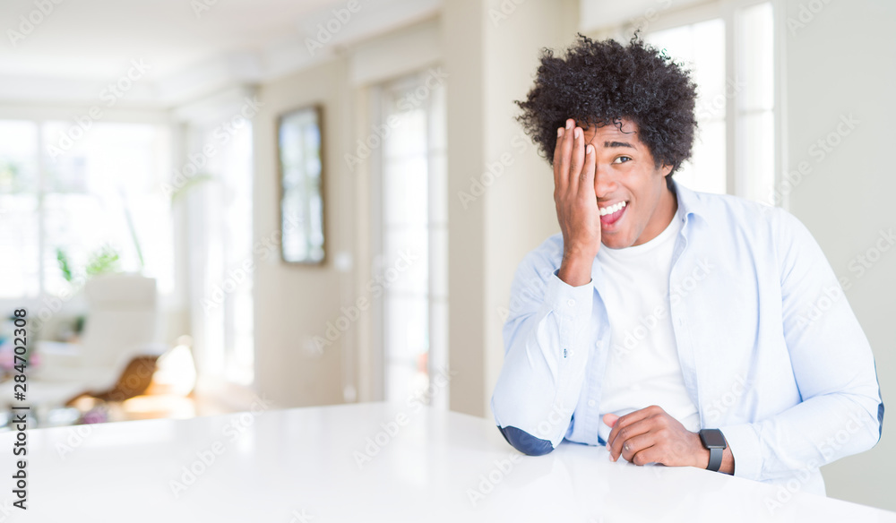 African American man at home covering one eye with hand with confident smile on face and surprise emotion. African American man at home covering one eye with hand with confident smile on face and surprise emotion.