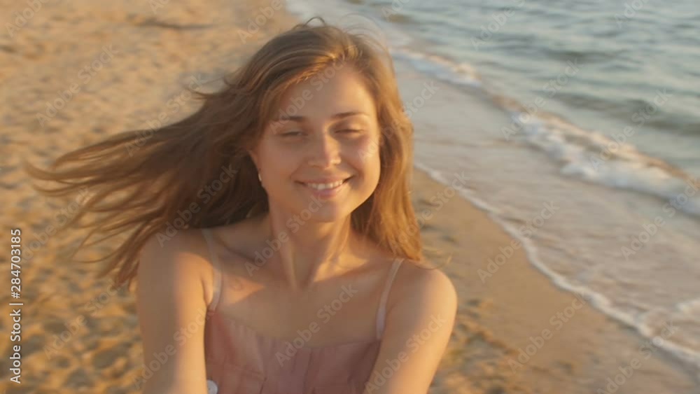 face of a happy girl spinning round at sunrise, woman holding hands of her beloved man, honeymoon at seashore, romantic vacation. Slow motion face of a happy girl spinning round at sunrise, woman holding hands of her beloved man, honeymoon at seashore, romantic vacation. Slow motion