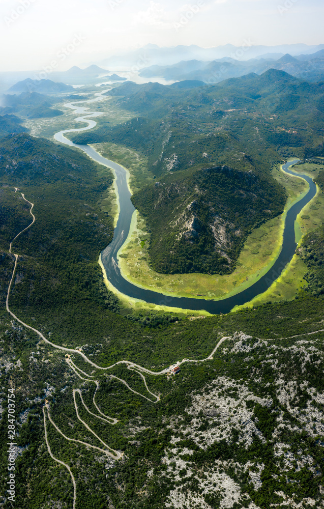 Aerial view of river Crnojevica leading to lake Skadar through a mountainous landscape. Lake Skadar National Park, Montenegro. Aerial view of river Crnojevica leading to lake Skadar through a mountainous landscape. Lake Skadar National Park, Montenegro.