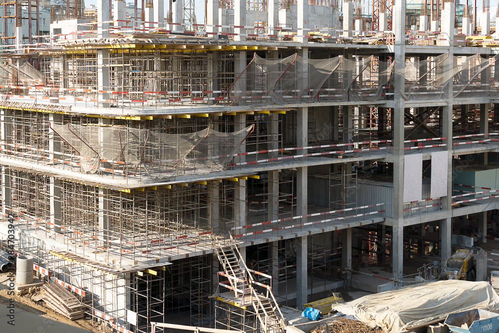 The construction of a multi-storey building. Construction iron scaffolding on several.