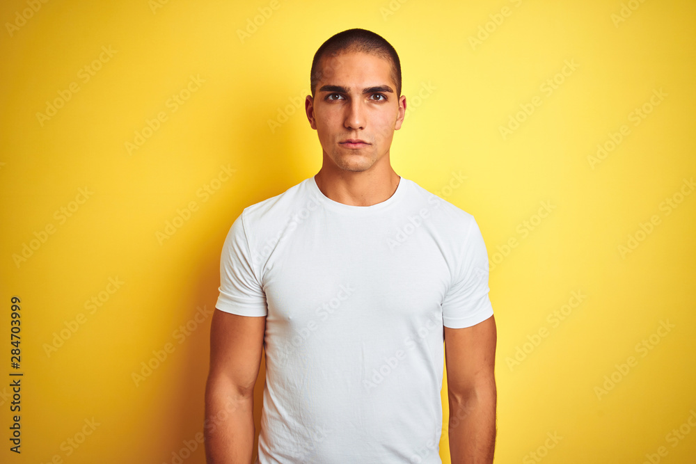 Young caucasian man wearing casual white t-shirt over yellow isolated background skeptic and nervous, frowning upset because of problem. Negative person. Young caucasian man wearing casual white t-shirt over yellow isolated background skeptic and nervous, frowning upset because of problem. Negative person.