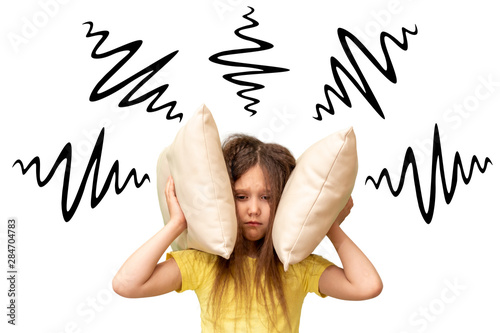 The little girl covered her ears with a pillow. Loud sound concept