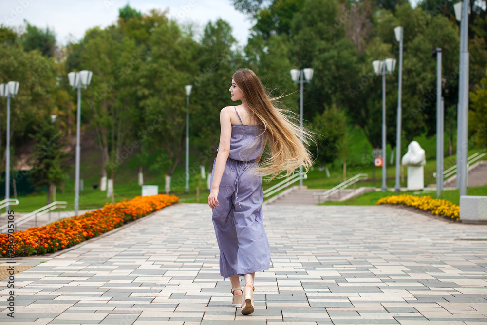 Young beautiful woman in gray dress walking on the summer street Young beautiful woman in gray dress walking on the summer street