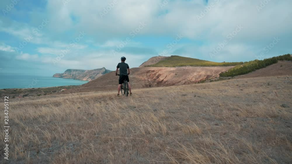 Riding mountain bike on hill at moderate speed and goes by the camera Riding mountain bike on hill at moderate speed and goes by the camera