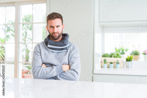 Handsome man at home skeptic and nervous, disapproving expression on face with crossed arms. Negative person.
