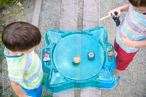 Two boys playing with a spinning top kid toy. Popular children game tournament. View from above